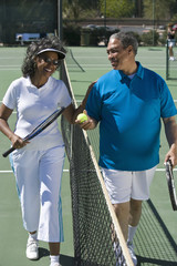 Happy African American couple playing together on tennis court
