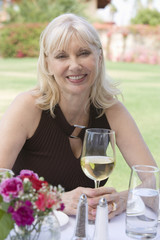 Portrait of a happy senior woman holding glass of wine at table