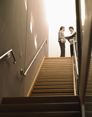 Happy multiethnic business people discussing with file standing by stairway