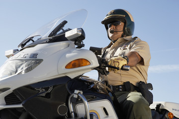 Low angle view of a mature police office riding motorbike