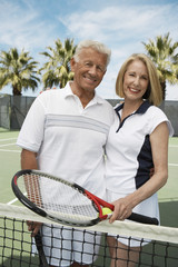 Portrait of happy senior couple in sportswear at tennis court