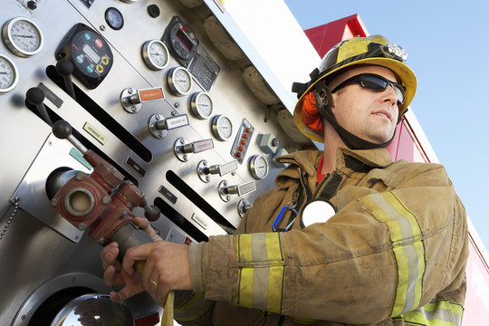 Low Angle View Of A Middle Aged Fire Fighter Holding Hose