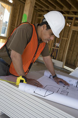 Architect looking at blueprint at construction site