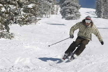 Full length of a young man skiing down snow covered slope