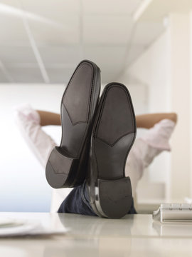 Businessman Reclining With His Feet Up On Desk In Office