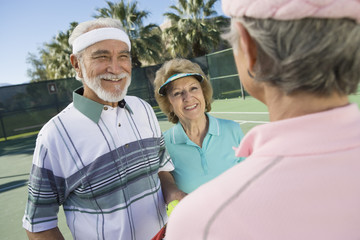 Happy senior tennis players chatting on court