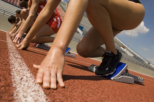 Cropped image of runners preparing for race at starting blocks