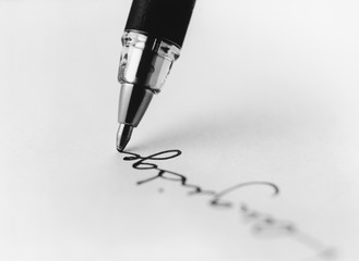 Fototapeta premium Tip of pen writing on paper (b&w) (close-up)