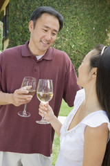 Happy mature Asian couple holding glasses of wine