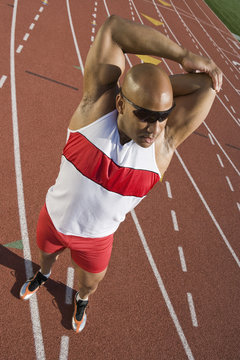 Full length of an African American male athlete stretching on race track