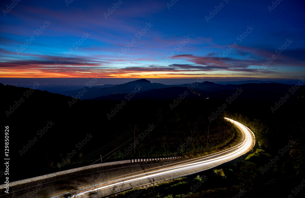 Wall mural long exposure car lights traveling along a road in the moutain.