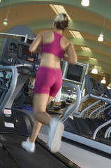 Fototapeta na wymiar Rear view of a woman running on a treadmill