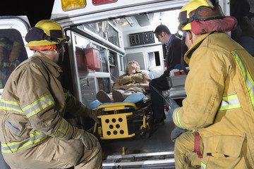 Fire workers looking at patient and EMT doctor in the ambulance © MDBPIXS