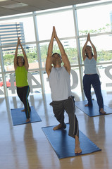 Multi ethnic people performing yoga on mat