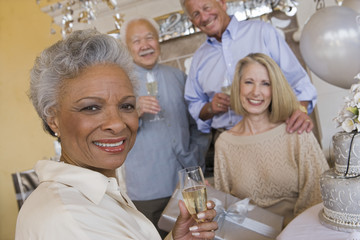 Portrait of an African American senior woman holding glass of champagne with friends in he background