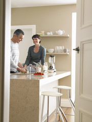 Happy woman looking at man washing utensils at kitchen counter