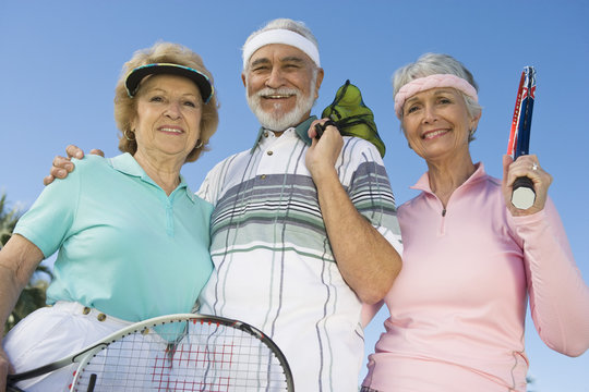 Happy senior man and women holding tennis racquets and balls