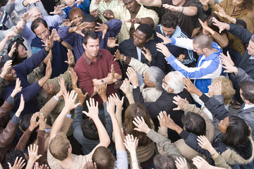 Portrait of a male celebrity standing with hands folded amidst around with fans