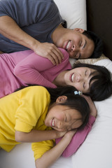 Happy family with daughter sleeping together in bed
