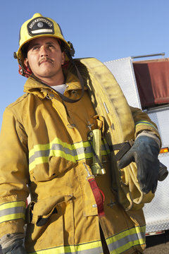 Mature adult fire worker carrying firehose on shoulder