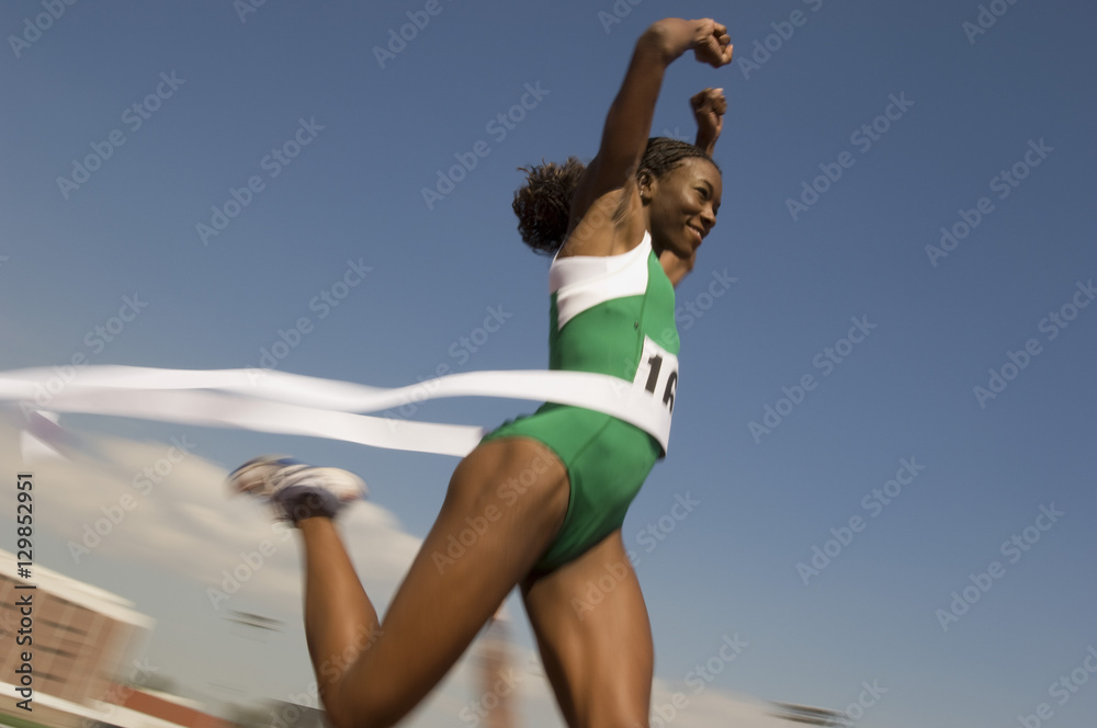 Wall mural african american female athlete crossing finish line in race