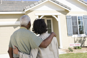 Rear view of African American couple standing in front of new house - Powered by Adobe
