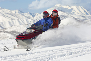 Multiethnic couple riding motor sledge on snow