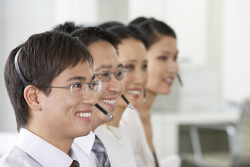 Row of customer service operators wearing headset in office