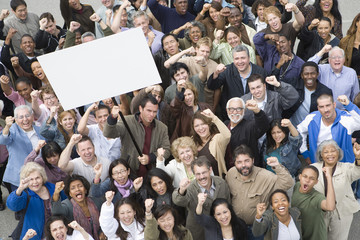High angle view of man raising billboard in rally with people supporting around him