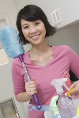 Portrait of a happy Asian woman holding cleaning equipments at home