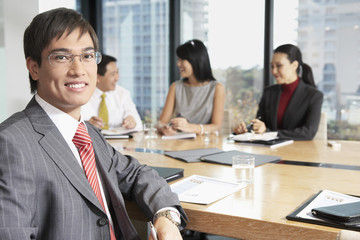 Portrait of confident young Asian businessman with colleague in boardroom