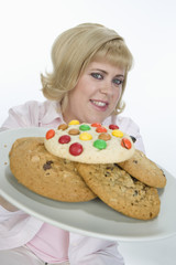 Portrait of mature woman holding plate of cookies isolated over white background