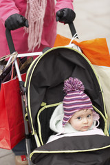 Low section of mother walking with baby in stroller