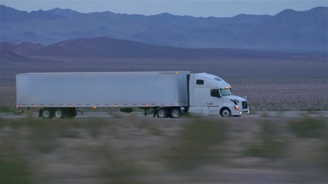 CLOSE UP: Freight semi truck driving and transporting goods on empty highway