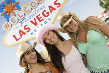 Portrait of beautiful female friends standing together with 'Welcome To Las Vegas' sign in the background © MDBPIXS