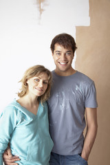 Portrait of happy couple embracing in front of partially painted wall