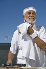Senior male tennis player sweeping out the sweat with napkin