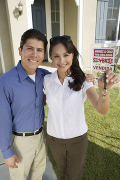 Portrait of a Hispanic couple holding keys of their new house
