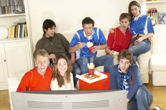 Group of friends watching football match in living room