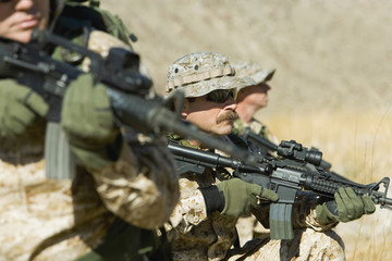 Three soldiers with rifles patrolling during war