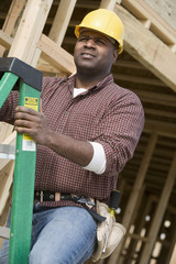 Manual worker climbing a ladder at construction site