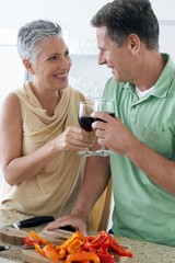 Senior couple standing together by holding wine glass at kitchen
