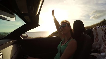 SLOW MOTION: Cheerful woman enjoying the ride in convertible at summer sunset