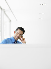 Portrait of smiling young businessman using cell phone at office