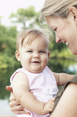 Closeup portrait of a cute daughter with smiling mother against the lake