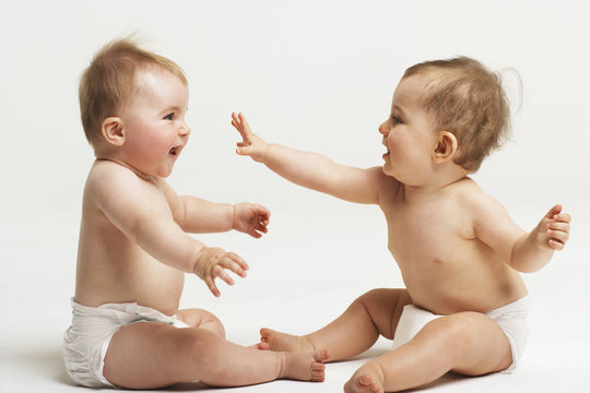 Side view of two babies playing on white background