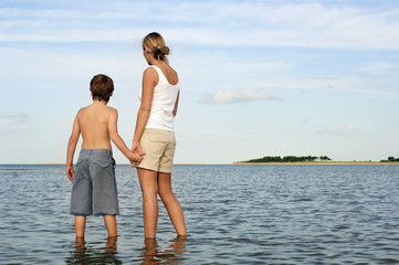 Rear view of mother and son holding hands while enjoying the sea view