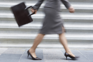 Blurred motion of a young businesswoman carrying laptop bag