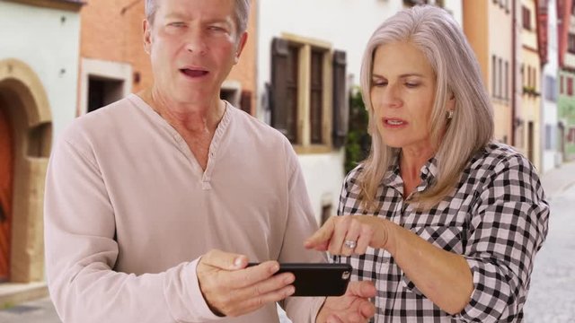 Couple of elderly caucasian people reading directions on smartphone device