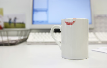 Lipstick print on coffee mug on computer desk